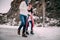 Young couple with cups of hot tea in their hands hold hands, smile and walking across puddle of melted water.