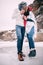 Young couple with cups of hot tea in their hands is kisssing and standing in puddle of melted water.