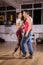 Young couple dancing social dance kizomba in big studio hall
