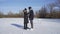 Young couple date on frozen lake. Woman wears skates and man wears sneakers