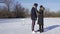 Young couple date on frozen lake. Woman wears skates and man wears sneakers