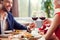 Young couple on date in restaurant sitting eating salad drinking wine cheers smiling cheerful close-up