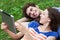 Young couple with digital tablet lying on grass