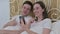 Young Couple doing Video Chat on Smartphone in Bed