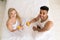 Young Couple Drink Orange Juice Sitting In Bed, Happy Smile Hispanic Man And Woman Top Angle View