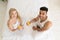 Young Couple Drink Orange Juice Sitting In Bed, Happy Smile Hispanic Man And Woman Top Angle View