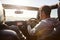 Young couple driving with sunroof open, rear passenger POV