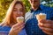 Young couple eating ice-cream and chatting outside. Woman and man chilling out in spring garden at sunset. Lifestyle