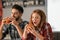 Young couple eating tasty burgers at home