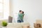 Young couple embraces and dances in the living room of their new apartment. The concept of affordable mortgage and new
