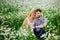 A young couple embraces outdoors in a field of daisies at sunset. The concept of passion and love