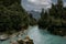 Young couple embracing each other while looking at the blue water in Hokitika Gorge. New Zealand, South Island