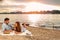 Young couple enjoying a picnic at the beach. Lying on the picnic blanket. White swans swimming the background