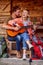 A young couple enjoys playing a guitar at cottage porch together. Vacation, relationship, cottage