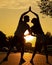 Young couple exercising on street near road in city from below view, sunset background. Darkened silhouettes of training