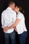 Young couple expecting baby standing together kiss in love back view indoors