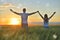 Young couple feeling free in a beautiful natural setting, in what field at sunset