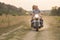 A young couple in the field next to the motorcycle