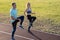 Young couple of fit sportsmen boy and girl running while doing exercise on red tracks of public stadium outdoors