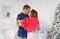 Young couple gently kiss in christmas decoration at home. Selective fokus in red box