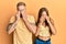 Young couple of girlfriend and boyfriend hugging and standing together rubbing eyes for fatigue and headache, sleepy and tired