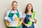 Young couple of girlfriend and boyfriend wearing apron holding products and cleaning spray smiling and laughing hard out loud