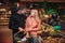 Young couple in grocery store. Cheerful man and woman look at each other and smile. He hold grocery basket in hands.