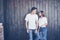 Young couple, guy and girl together on a wooden wall background. They are happy together and dressed alike. Always in a