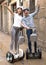 young couple guy and girl walking on self-propelled vehicles in streets of european city