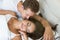 Young couple handsome husband kissing his beautiful sleeping wife in bed in bright bedroomfeeling happy family morning