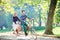 Young couple, handsome man and attractive woman on tandem bike in sunny summer park or forest.