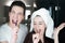 Young couple handsome smiling man and beautiful woman in turban with toothbrushes in their hands singing in bathroom in the