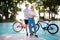 Young couple happily looking on each other with red and blue bicycles on background. Joyful boy standing with beautiful
