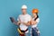 Young couple in hardhats using laptop during house repair, blue background