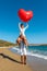 Young couple having fun on the beach with a big heart balloon. Summer love concept