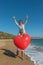 Young couple having fun on the beach with a big heart balloon. Summer love concept