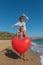 Young couple having fun on the beach with a big heart balloon. Summer love concept