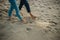 A young couple is having fun and walking on the sea coastline. Legs close up. Romantic date on the beach