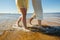 A young couple is having fun and walking on the sea water. Legs close up. Romantic date on the beach