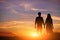 Young couple is holding hands on a background sunset silhouette