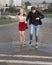 Young couple holding hands run on street with splashing in puddles