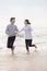 Young couple holding hands and running by the waters edge on the beach, China