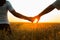 Young couple holding hands in the wheat field