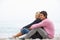 Young Couple On Holiday Sitting On Winter Beach