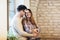 Young couple hugging next to the window, brick wall background