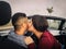 Young couple kiss in a convertible car during their road trip - Happy romantic newlywed date driving a cabriolet auto in honeymoon