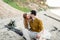 A young couple kisses on the beach. Bride and groom hugging on the log. Close-up portrait