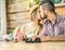 Young couple kissing at cafe bar restaurant - Two lovers having tender moments during vacation with flower plant at bottom right