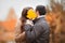 Young couple kissing, hiding faces with autumn yellow maple leave.