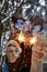 young couple kissing and holding sparklers on a background of snow-covered park and trees, loving couple, smiles on